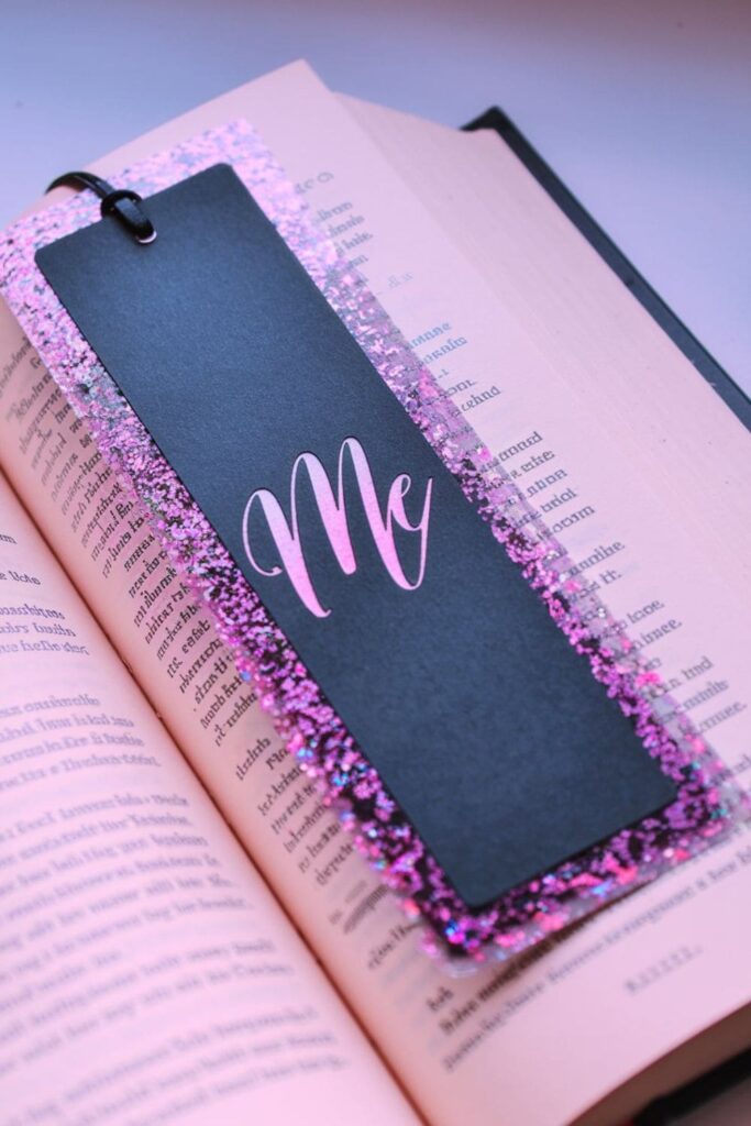 A sleek cardstock bookmark with shimmering gold and silver glitter along the edges, adding a touch of sparkle and elegance to the reading experience